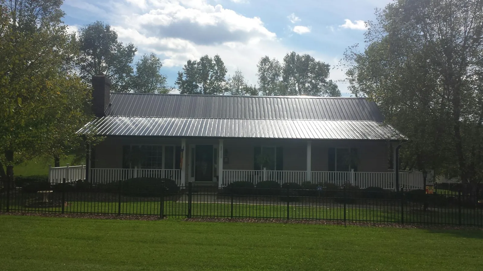Gray metal roof on a brick ranch with a full width front porch — Gutter Guard Installation work by our crew in Johnston