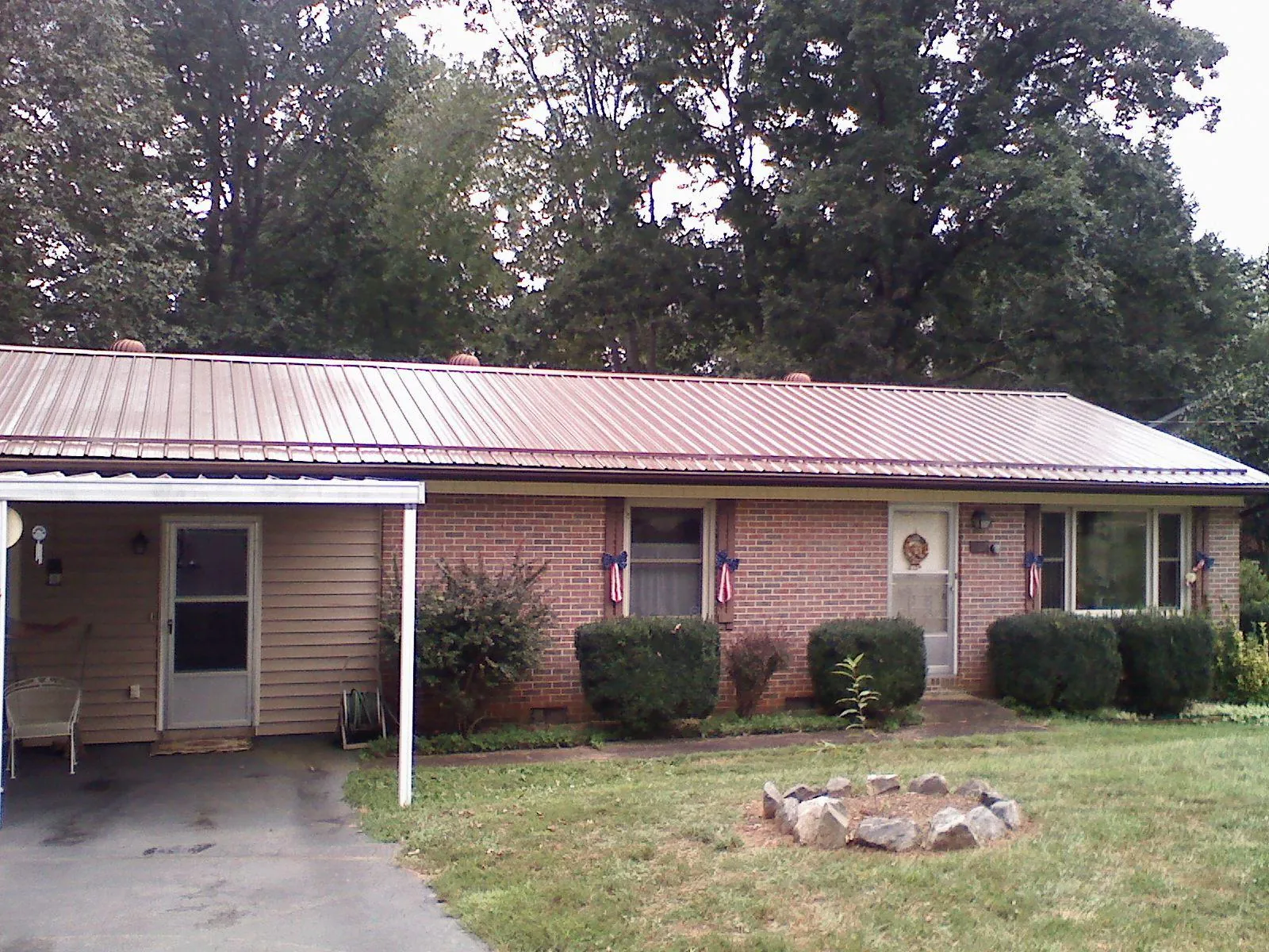 Bronze metal roof and carport on a brick ranch home — Roof Repair work by our crew in Johnston